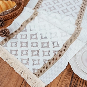 Boho ivory geometric table runner with brown lace trim and fringe on wood table
