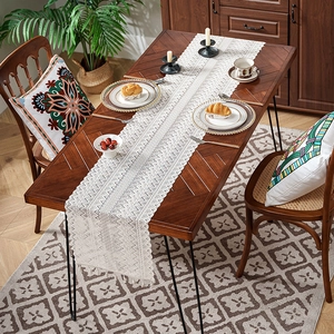 White hollow lace table runner with geometric crochet patterns and tassel fringe decor