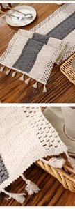 Detail of bohemian woven table runner featuring handmade tassels and crochet patterns