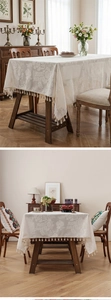 Detail of cream floral jacquard tablecloth with elegant fringe tassels for dining tables