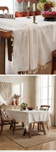 Detailed close-up of cream vintage tablecloth featuring relief jacquard texture and fringes