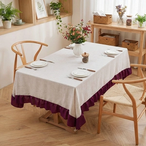 Minimalist beige linen tablecloth with purple pleated ruffle hem on a wooden dining table