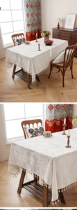 Detail of white jacquard tablecloth with floral patterns and delicate tassel fringes