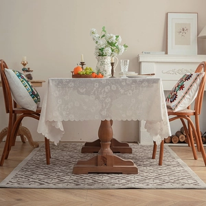 Close-up of white lace tablecloth with floral hollow patterns and scalloped edges