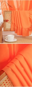 Close-up of bright orange sheer curtain featuring elegant ruffled edges and soft texture