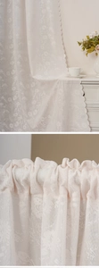 Detail of white lace door curtain featuring floral embroidery and scalloped wave edges