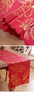 Detail of red velvet table runner with gold feather patterns and scalloped edges