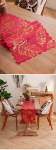 Detail of red table runner with gold feather patterns and red handmade lace edges