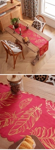 Close-up of golden feather prints and wavy edges on a luxury red table runner fabric