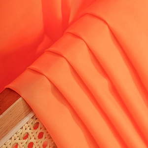 Minimalist bright orange sheer curtain fabric with delicate texture on rattan chair