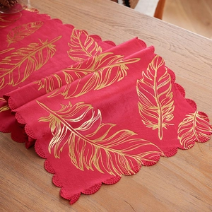 Elegant red velvet table runner with metallic gold feather patterns and wavy lace borders