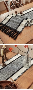 Close-up of bohemian woven table runner with black and white texture and long tassels