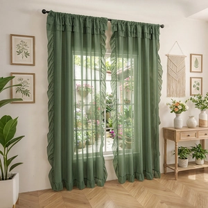Dark green sheer curtains with romantic ruffles in a cozy home setting with indoor plants