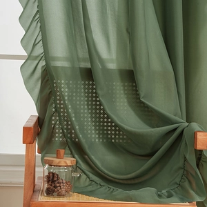 Dark green sheer voile curtain with ruffled edges draped elegantly on a wicker chair
