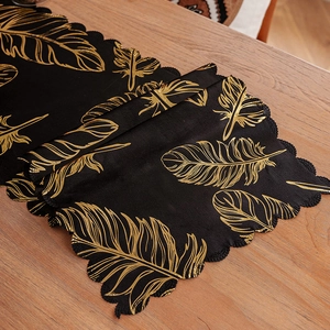 Luxurious black table runner with metallic gold feather patterns and wavy edges