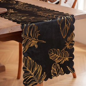 Luxurious black velvet table runner with gold feather patterns and wavy scalloped edges