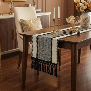 Modern woven table runner with black and white geometric patterns and tassel fringe décor