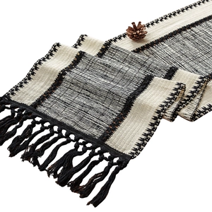 Modern black and white woven table runner with geometric textures and fringe tassels