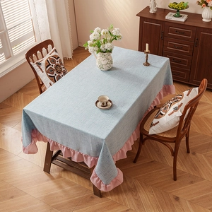 Pastel blue linen table cloth with pink ruffled edges on a rectangle wooden table