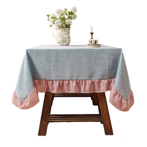 Linen style blue grey tablecloth with pink ruffled edges on a rustic wooden table
