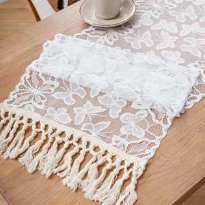 Elegant white lace table runner with butterfly patterns and handmade beige tassels on wood