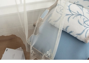 Close-up of white translucent lace window curtain featuring elegant vintage floral edges