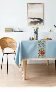 Detail of light blue cotton linen tablecloth featuring floral embroidery and lace trim edges