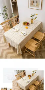 Close-up of light beige linen tablecloth with dark brown grid pattern and tassel edges