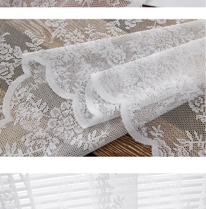 Detail of white lace curtain fabric featuring floral embroidery and scalloped edges