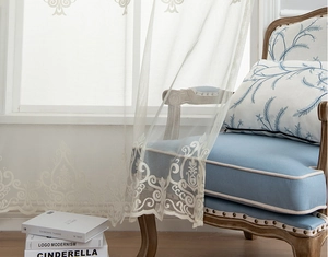 Close-up of white sheer lace curtain with elegant European style floral embroidery details