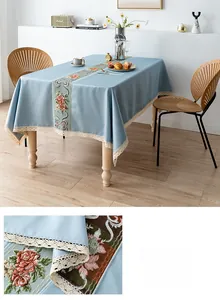 Detail of blue linen tablecloth featuring floral embroidery and white lace edges
