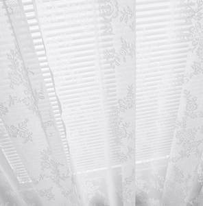 Close-up of elegant white lace curtain featuring delicate floral embroidery and mesh texture