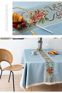 Close-up of elegant rose embroidery and lace border on a blue fabric tablecloth