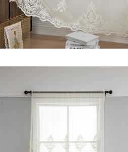 Detail of white damask floral embroidery on sheer lace curtain with black tassel accent