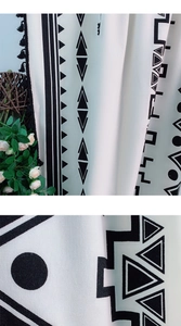 Detalle de cortina de cocina bohemia de algodón y lino con estampados negros y borlas