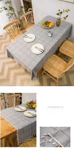 Detail of grey checkered tablecloth with tassels on textured cotton linen fabric