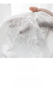 Detailed macro view showing the intricate floral lace embroidery and soft texture of white sheer curtain