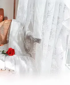 Detail of white lace sheer curtain with floral jacquard pattern draped on vintage chair