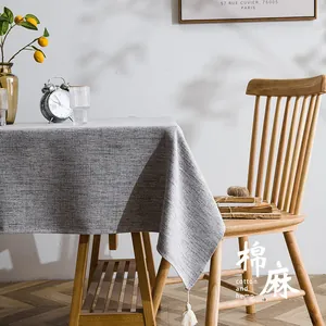 Detail of grey cotton hemp tablecloth featuring elegant beige tassels and linen texture