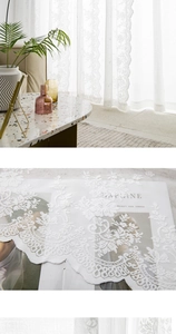 Detail of white lace curtain with floral embroidery and elegant scalloped wavy edges