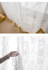 Detail of white floral lace curtain with ruffled edges and sheer mesh texture