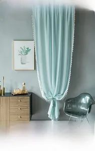 Close-up of light blue sheer curtains with white tassel edges and smooth texture