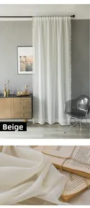 Detail of beige sheer curtain with pom-pom trim and linen texture in modern room