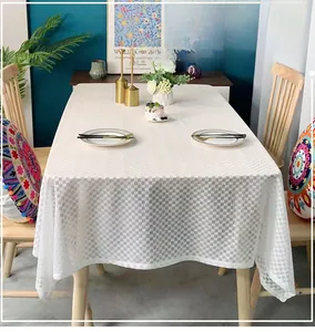 Detail view of white translucent grid pattern tablecloth on rectangular wooden dining table