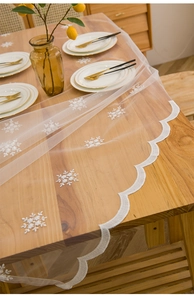 Détail de la nappe en dentelle blanche avec broderie flocon et bordure festonnée
