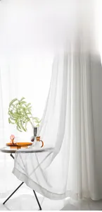 Detailed close-up of white semi-transparent lace curtains with elegant hollow patterns