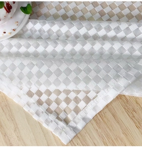 Close-up of cream checkerboard mesh tablecloth texture on a light wood surface