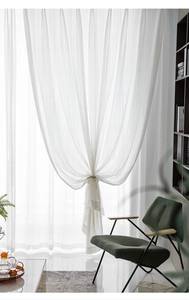 Close-up of white lace curtain showing delicate floral patterns and elegant vertical textures