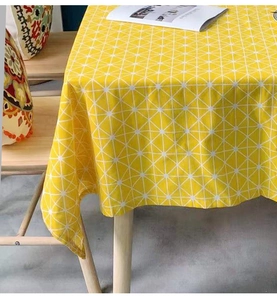 Detail der gelben Tischdecke mit weißem geometrischem Gitter auf Holztisch