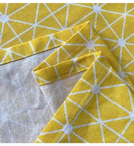 Makroansicht gelber Stoff in Leinenoptik mit weißen geometrischen Mustern und Saumnaht